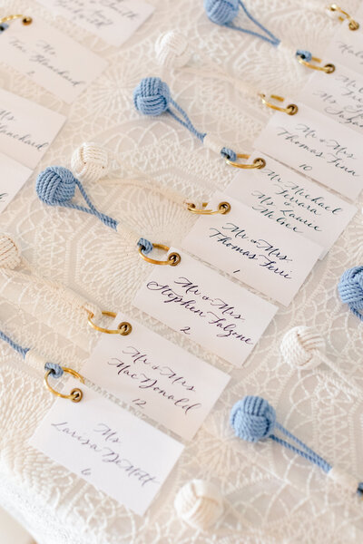 White escort cards with navy blue calligraphy attached to Mystic Knotwork monkey's fist knot keychains for Belle Haven wedding in Greenwich, Connecticut