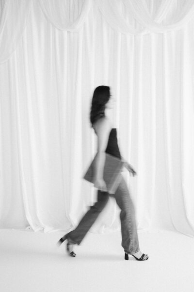 A wedding photographer leaning down and adjusting a wedding dress train 
