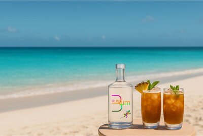 The Original Rum Bum Signature No1 Blend Rum, next to two cocktails on a Caribbean beach