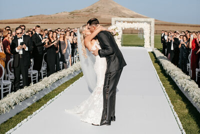 bride and groom kissing walking down the aisle