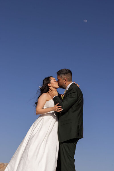 Couple kissing beneath clear blue skies during their Utah elopement, captured by Lamblight Photography