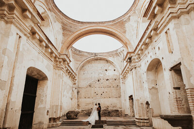bride and groom kissing under stone archways