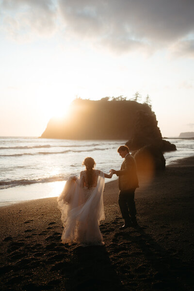 Olympic National Park elopement on Ruby Beach, couple walks towards the sunset holding hands