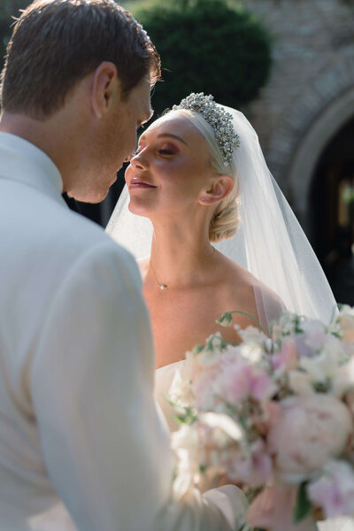 close up of bride and groom embracing smiling at each-other in the gardens of euridge manor wedding venue as the bride holds a pink bouquet