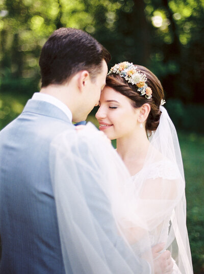 Bride and groom stand forehead to forehead and smiling on their wedding day