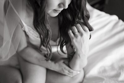 a black and white portrait of a bride sitting on a bed