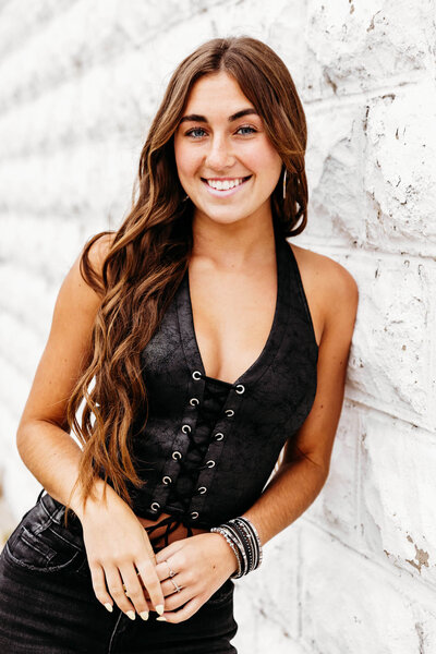 beautiful brunette teenage girl leaning against a white wall captured by Ashley Kalbus