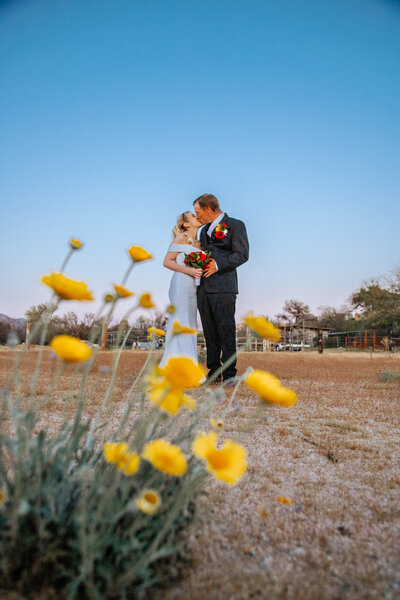 bride and groom kiss infront of flowers in phoenix arizona