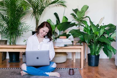 Woman creating systems on her computer sitting in an office space with plants.