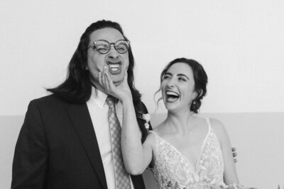 Black and white image of bride squishing her brother's face