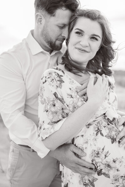 sun-drenched portrait of an expecting mom nuzzling her husband during maternity photos in virginia beach
