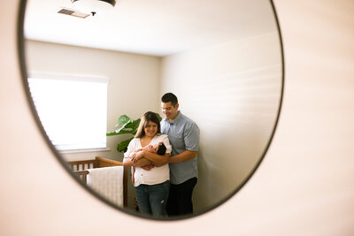Couple holding their newborn baby in her nursery for an in-home lifestyle newborn photography session. 