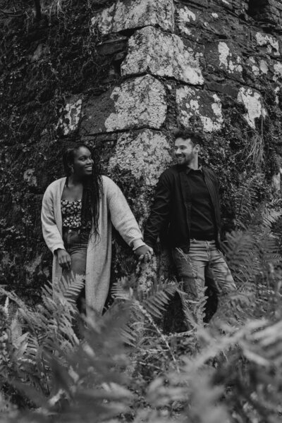 A couple pose for engagement photos in a rugged woodland.