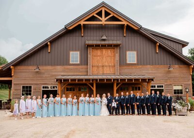 Large brial party photos in front of barn wedding venue