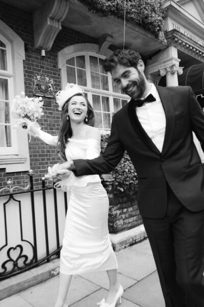 A black and white wedding photo of the bride ad groom on the streets of London celebrating