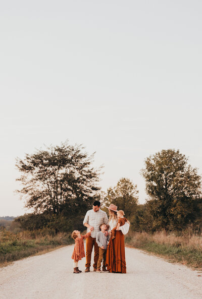 Family session of parents and children standing on stone road