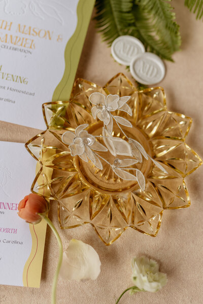 Grey Cove Designs romantic wedding flatlay featuring a custom invitation suite, white wax seals, crystal dish with floral earrings, and soft spring florals.