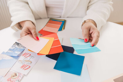 Close up of Leith's hands looking through colour swatches for a branding project