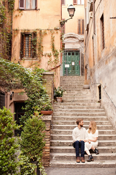 A couple sitting on the stairs of a classic roman home in Cento Storico. Taken by Rome Photographer, Tricia Anne Photography.