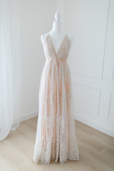 A photo of a beautiful lace gown on a white manequin.
