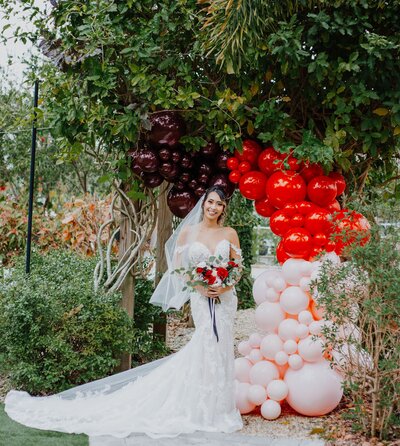 Bride in front of an organic balloon garland on a tree by Loononna, LLC in Orlando, FL.