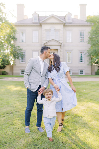 Family embracing in a field with tall grass.