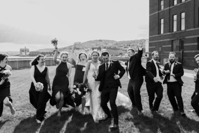 A newlywed couple and their wedding parties running together 