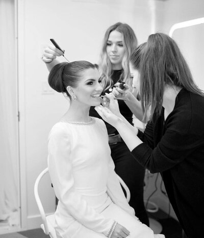 Black and white photo of a bride having her hair and makeup done.