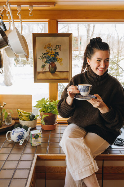 Woman sitting on a kitchen countertop drinking tea