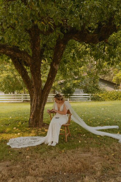 Bride sitting in a chair writing her vows before her ceremony