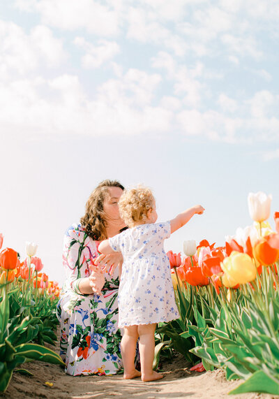 A little girl points at the sky with her mother in the tulip fields in Holland. 