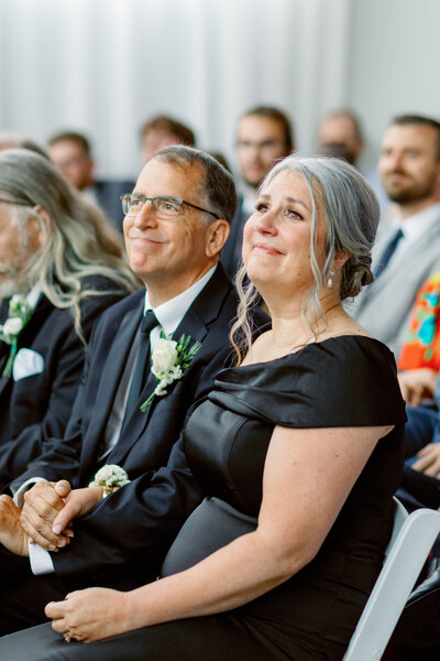 Parents of the bride look lovingly toward the couple during their ceremony at The Highline.