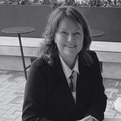 Jessica wearing a white blazer, smiling as she writes in her planner