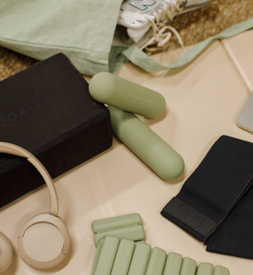 Detailed shot of green bala hand weights, ankle weights, headphones and a workout tote.
