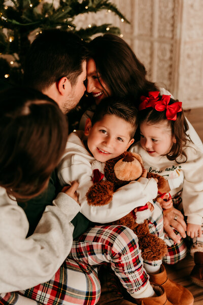 Family of five snuggled together in Christmas pajamas during a warm and playful in-studio holiday mini session with Brittani Luce Photography

