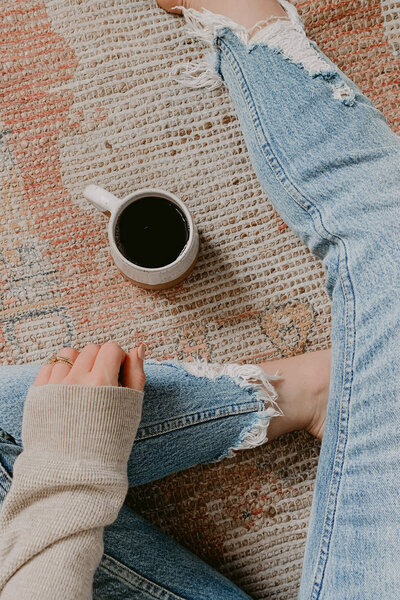 woman sitting cross-legged on the floor with a cup of coffee