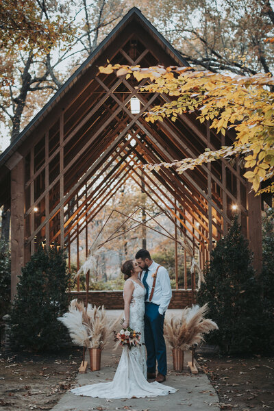 A bride and groom kiss under an arch at Memphis Botanic Garden