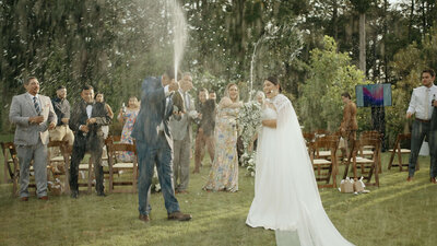 The bride and groom popped champagne and celebrate with splashes after the wedding ceremony in the garden.