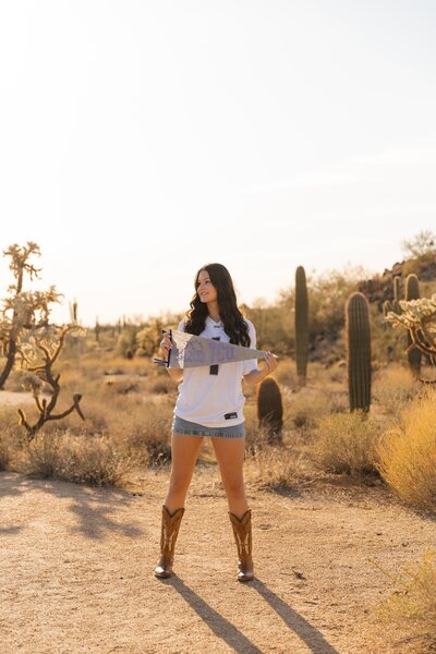 girl holds TCU flag in arizona desert for graduation photos