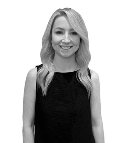 Smiling female Art Director with soft wavy blonde hair in a sleeveless black top, specialising in professional hair styling and management.
