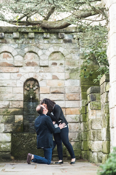 A person kissing their partner who is on their knees proposing 