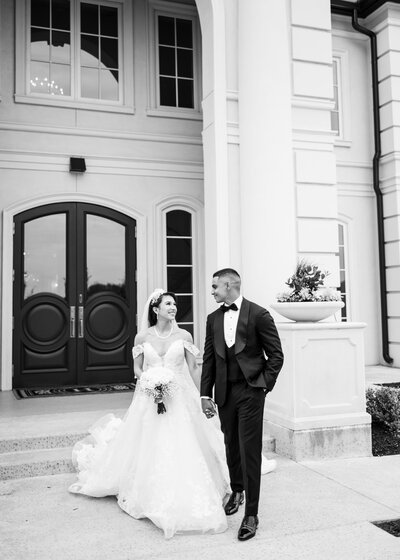 bride ans groom walking in front of a building holding hands
