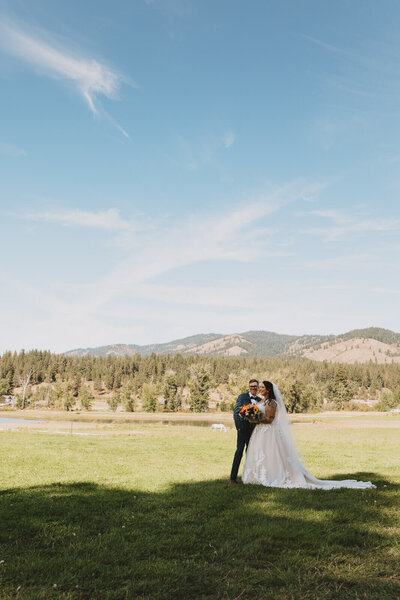 Bride and groom with mountain backdrop on sunny day