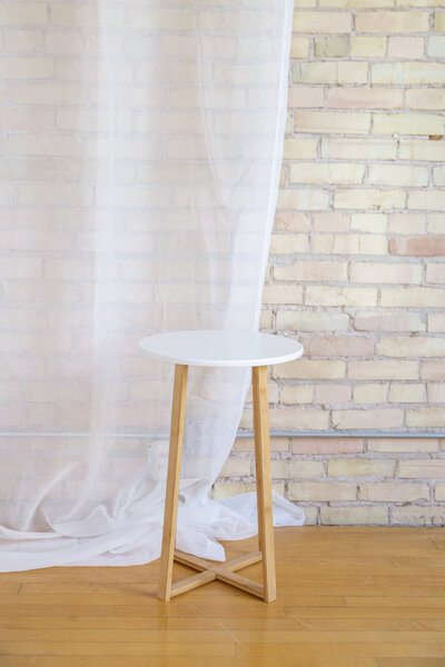 A small round white end table with wooden legs.