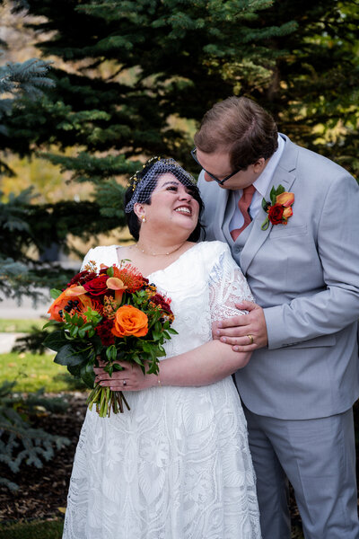 Bride and groom looking at each other bride holding bright bridal bouquet