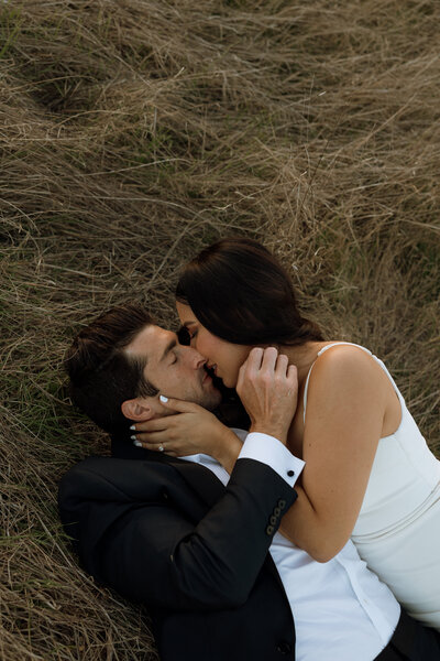 bride and groom kissing laying down 