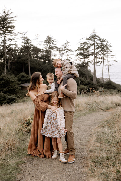 Lubbock family of five standing on a pathway. Dad has the older son on his shoulder, mama is holding baby brother on her hip and sister is standing in front of mom.