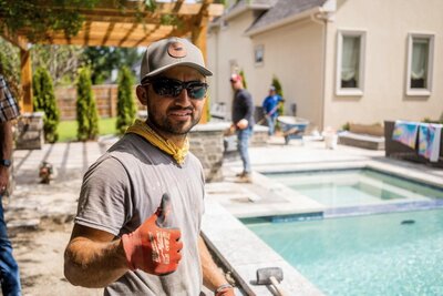 Better Lawns and Gardens crew member giving a thumbs up during a custom pool installation at a residential property in Little Rock, Arkansas.

