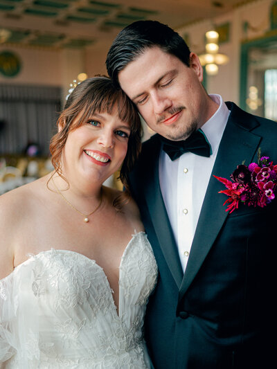 A bride and groom lean their heads together during their wedding portraits.