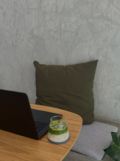 A laptop and glass of matcha sitting on a table